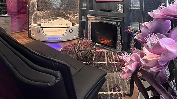 A modern living room with a large flat-screen TV, a fireplace, a massage chair, and a decorative wall. - Urban Suite With Jaccuzzi on Shopping Street (Wien)
