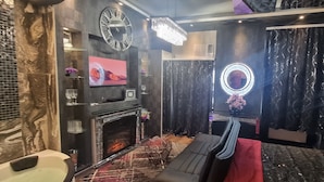 A modern living room with a fireplace, a large mirror, and a chandelier. - Urban Suite With Jaccuzzi on Shopping Street (Wien)