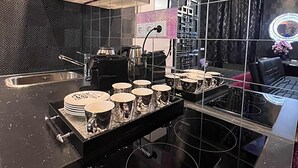 A modern kitchen with a black countertop, stainless steel appliances, and a glass shelf with cups. - Urban Suite With Jaccuzzi on Shopping Street (Wien)