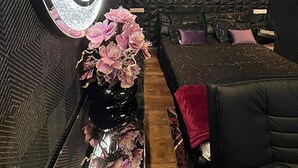 A modern room with a large mirror, a black sofa, and a decorative vase with flowers. - Urban Suite With Jaccuzzi on Shopping Street (Wien)