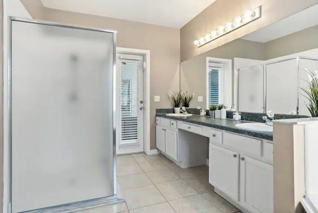 Un baño moderno con un espejo grande, armarios blancos y un lavabo con pileta.