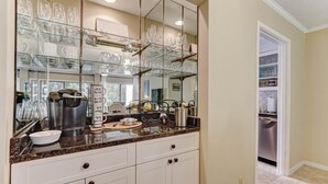A kitchen with a granite countertop, white cabinets, and a large mirror above the sink. - Pet & EV-Friendly Fairway Oaks, Steps to Golf! (Fernandina Beach)