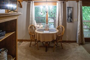 Un coin repas avec une table ronde, des chaises, un lustre et une vue par la fenêtre.
