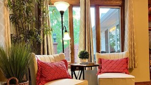 Un coin salon confortable avec deux fauteuils rembourrés, une petite table et une plante en pot.
