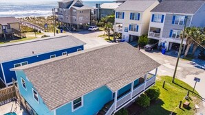 A two-story house with a balcony, a swimming pool, and a view of the ocean.