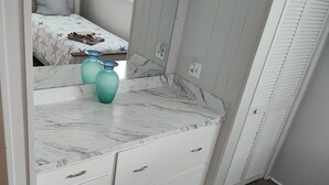 A bedroom with a bed, a dresser with drawers, a mirror, and a window.