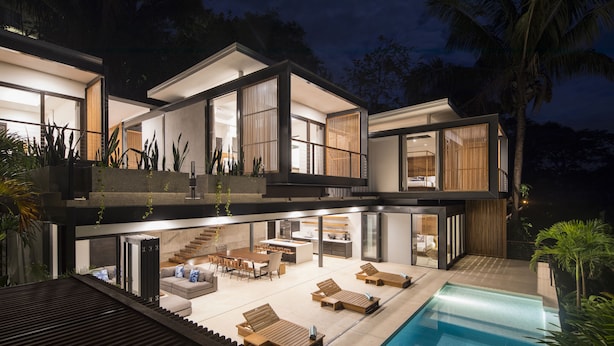 Una casa moderna de dos pisos con un amplio salón integrado, un comedor y una piscina.
