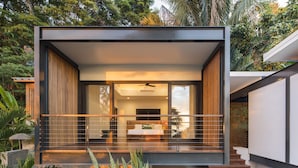 Una casa moderna con balcón, ventanas amplias y una escalera que conduce a la entrada.