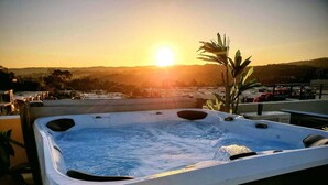 A hot tub on a rooftop with a sunset view.