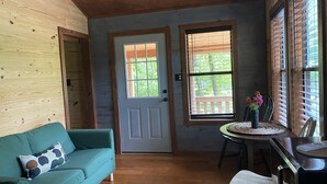A cozy room with a teal sofa, a wooden door, and a window with blinds.