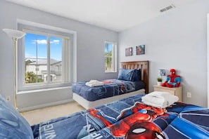 Un dormitorio con dos camas, una ventana y un peluche de Spiderman.