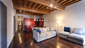 A spacious living area with a wooden ceiling, a kitchen in the background, and two sofas. - Piazza Navona Mara’s apartment (Roma)