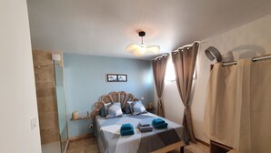 Ein Schlafzimmer mit Bett, einer Pendelleuchte, Vorhängen und einem kleinen Tisch.