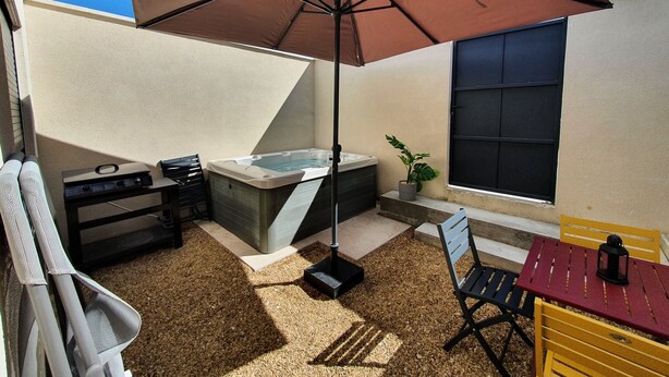 Eine Terrassenanlage mit Whirlpool, Tisch, Stühlen und einer Topfpflanze.