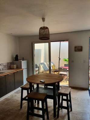 A kitchen with a dining area, a ceiling fan, and a view of outdoor chairs and a table through a glass door. - New gite with private spa (Jonquerettes)