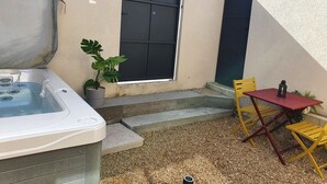 Eine kleine Außenpatio mit Whirlpool, Tisch und Stühlen.