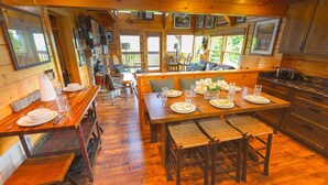 A wooden cabin interior with a dining area, wooden benches, and a kitchen. - High Mountain Mist - A Beautiful 4 Bedroom Cabin in Starr Crest Resort w/ Hot Tub and Pool Table! (Sevierville)