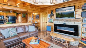 A cozy cabin interior with a wooden interior, a fireplace, a large TV, and a sign reading "Great Smoky Mountain". - High Mountain Mist - A Beautiful 4 Bedroom Cabin in Starr Crest Resort w/ Hot Tub and Pool Table! (Sevierville)