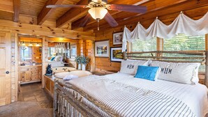 A wooden cabin interior with a bed, ceiling fan, and large windows. - High Mountain Mist - A Beautiful 4 Bedroom Cabin in Starr Crest Resort w/ Hot Tub and Pool Table! (Sevierville)