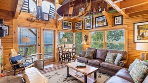 A cozy cabin interior with a wooden interior, a leather sofa, a dining area, and a loft space with a telescope. - High Mountain Mist - A Beautiful 4 Bedroom Cabin in Starr Crest Resort w/ Hot Tub and Pool Table! (Sevierville)