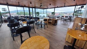 Un vaste espace intérieur aménagé avec différents types de sièges, notamment des tables et des chaises, et offrant une vue sur le paysage urbain grâce à de grandes fenêtres.