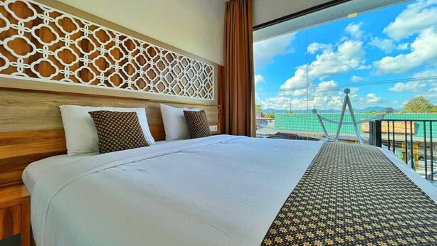 Une chambre d’hôtel avec un grand lit, une tête de lit décorative et une vue sur le ciel et les bâtiments.