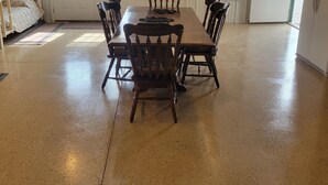 A spacious room with a large wooden dining table and chairs, a bunk bed, and a refrigerator.