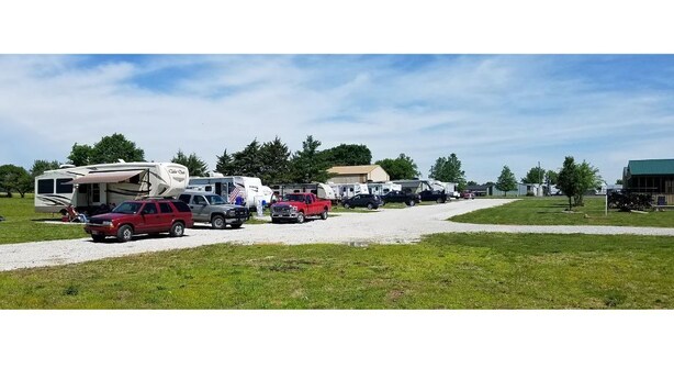 A campground with RVs and cars parked on a gravel path.
