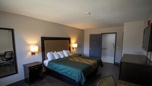 Quarto de hotel com cama, abajures, escrivaninha, cadeira e espelho.