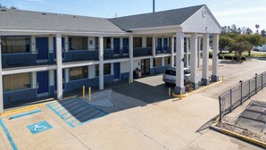 Um motel com estrutura em dois andares, entrada coberta e vaga para deficientes.