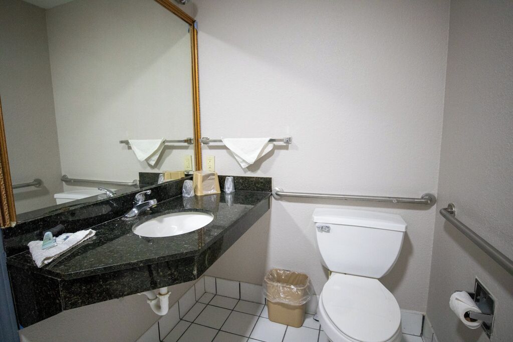 Une salle de bain avec un lavabo en marbre noir, des toilettes blanches et un miroir.
