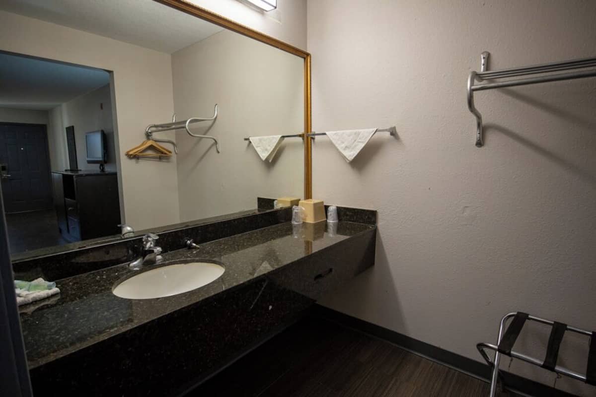 A bathroom with a black granite sink, a mirror, and a towel rack.