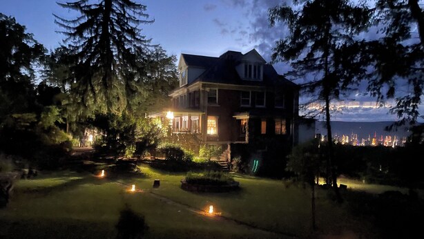 Una casa grande con un césped cuidado y varias velas encendidas.