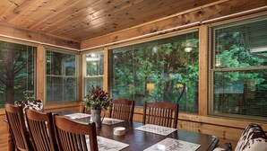 A wooden-paneled room with a large table set for dining, surrounded by chairs. - Charming Cozy Cabin by the Smoky Mtns. Game Room, Fireplace, Sunroom, Fire Pit (Sevierville)