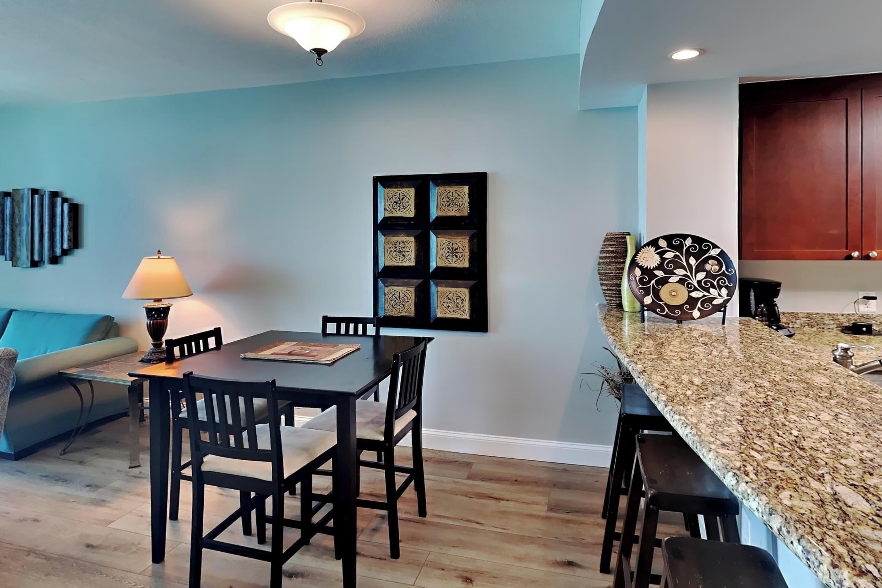 Una cocina moderna con encimera de granito, sillas de madera y una mesa de comedor.