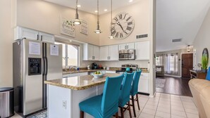 A modern kitchen with a central island, stainless steel appliances, and a large wall clock. - Resort Style Home, Private"Heated Pool", Near Phoenix.Putting Green, Pool Table. (Mesa)
