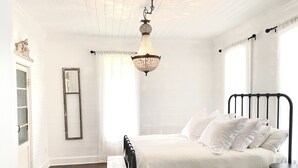Une chambre à coucher avec un lit, un lustre, une fenêtre et une porte.