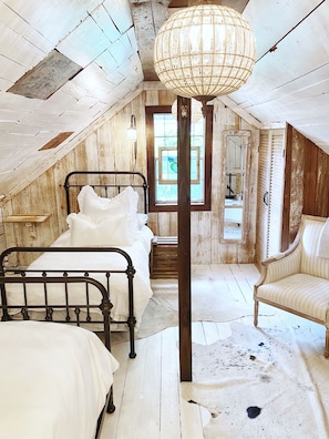 Ein rustikales Schlafzimmer im Dachgeschoss mit einem Bett, einem Sessel und einer Pendelleuchte.