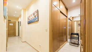 Un pasillo con un armario de madera, una silla plegable y un cuadro en la pared.