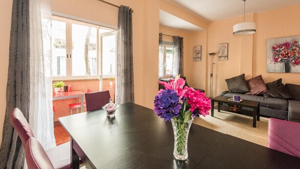 Una sala de estar moderna con una mesa de madera oscura, un sofá y un comedor con una silla roja y una mesita.
