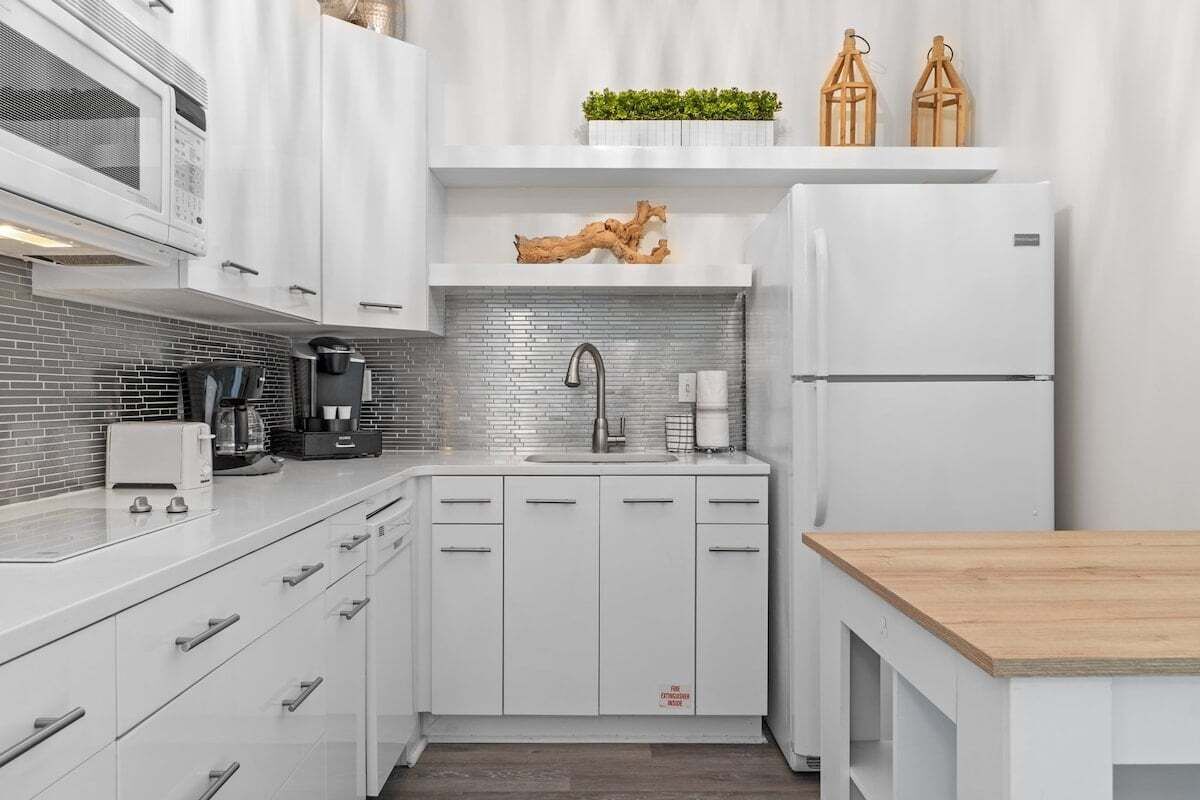 A modern kitchen with white cabinetry, a stainless steel sink, and a built-in microwave.