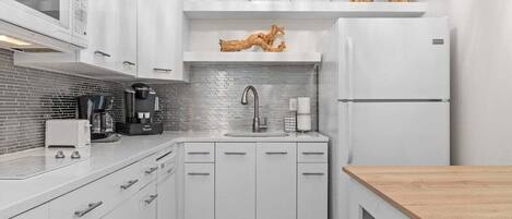 A modern kitchen with white cabinetry, a stainless steel sink, and a built-in microwave.