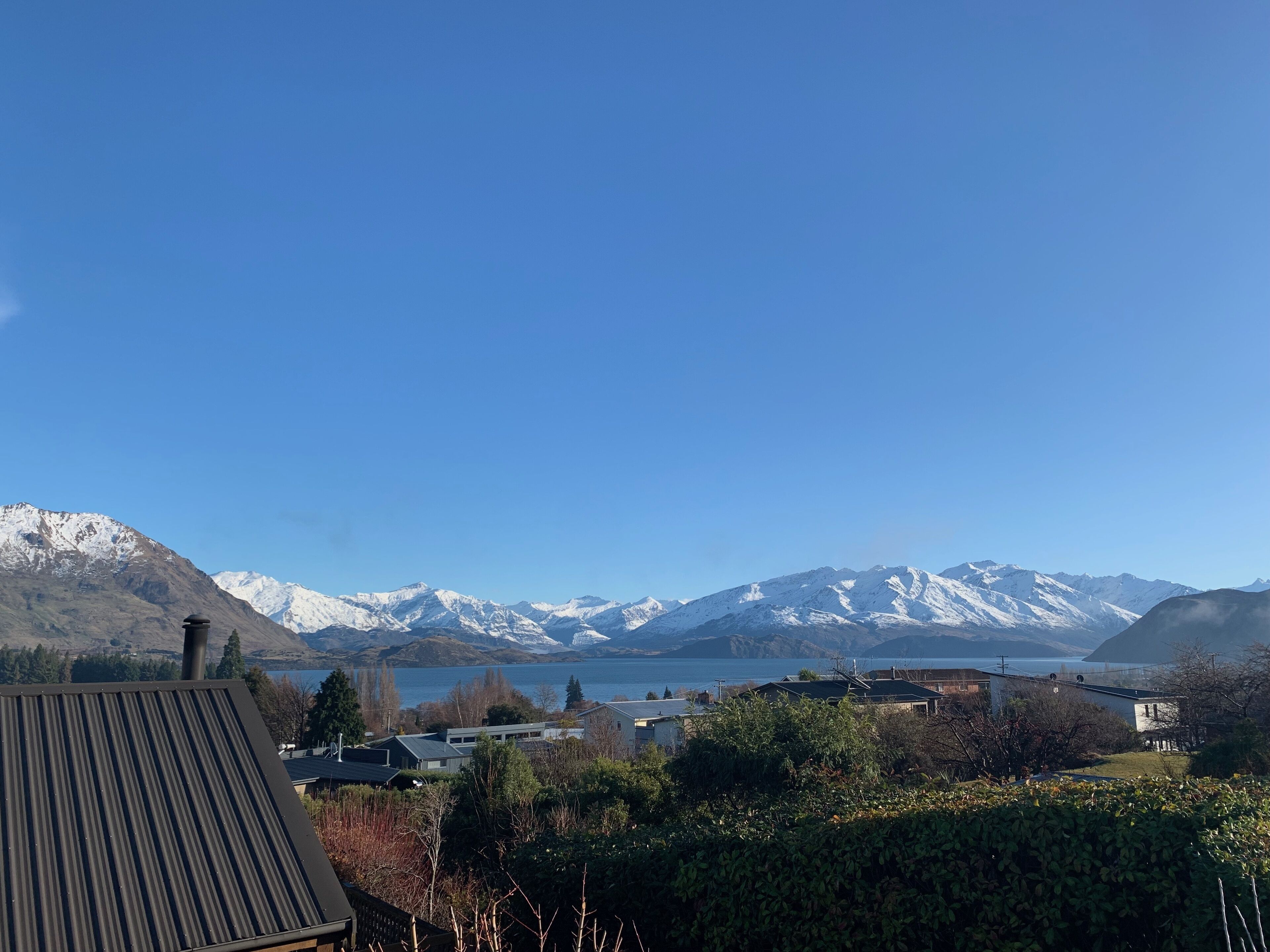 A view of a mountainous landscape with snow-capped peaks and a body of water in the foreground.