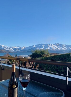 A table with a wine bottle and glass, overlooking a mountainous landscape. - AspiringLofts (Wanaka)
