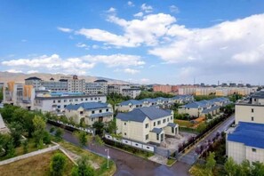 Un quartier résidentiel avec des bâtiments modernes, un ciel dégagé et une chaîne de montagnes à l’horizon.
