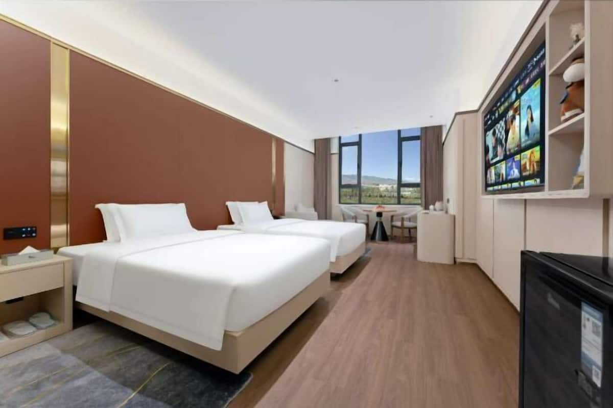 Ein Hotelzimmer mit zwei Betten, einem Schreibtisch, einem Fernseher und Blick ins Freie.
