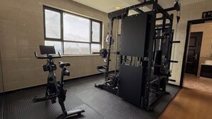 Ein Fitnessraum mit einer Hantelbank, einem Squat-Gestell und einem Ergometer.