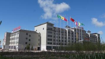Un hotel de varios pisos con un diseño arquitectónico moderno, que destaca por su entrada principal y múltiples banderas.