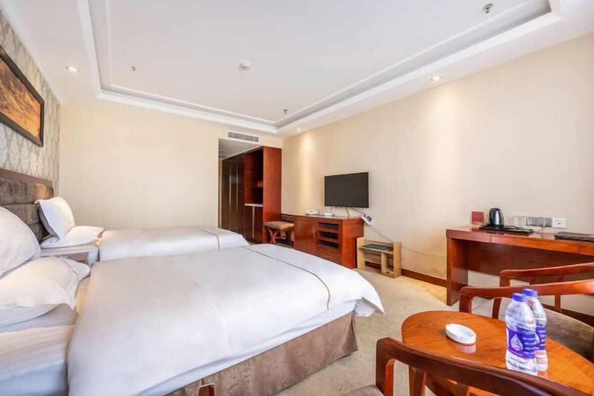 A hotel room with a large bed, a desk with a computer, a TV, and a chair.