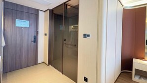 Ein Hotelkorridor mit Holztür, Glastür und weißer Wand inklusive einer kleinen Ablagefläche.